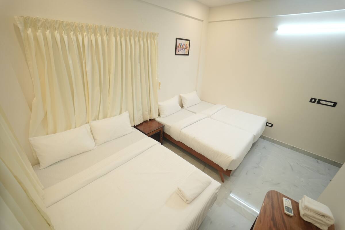 A hotel room with two beds, a wooden nightstand, a telephone, and a framed picture on the wall.