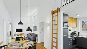 Una cucina moderna con mobili grigi, una scala in legno e un'area pranzo con un tavolo rotondo e sedie.
