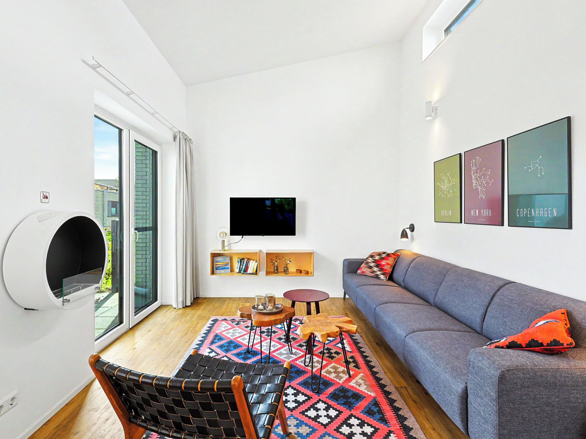 A modern living room with a sofa, a TV, a bookshelf, and a patterned rug.