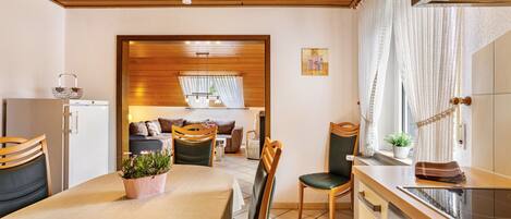 Cocina compacta con comedor, techo de madera y vista al salón.