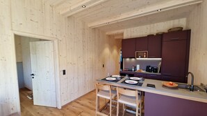 Een kleine keuken met houten wanden en een centraal eiland, voorzien van moderne apparatuur en zitplaatsen voor twee personen.