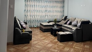 A living room with a sectional sofa, a small table with a plant, and a patterned curtain. - All sur machupicchu  (Aguas Calientes)