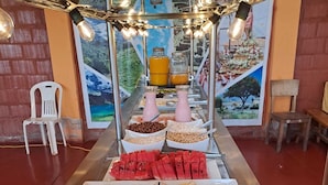A buffet with various food items including watermelon, orange slices, and nuts. - All sur machupicchu  (Aguas Calientes)