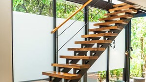 Una escalera moderna con escalones de madera y barandilla de metal que conduce a un segundo piso.
