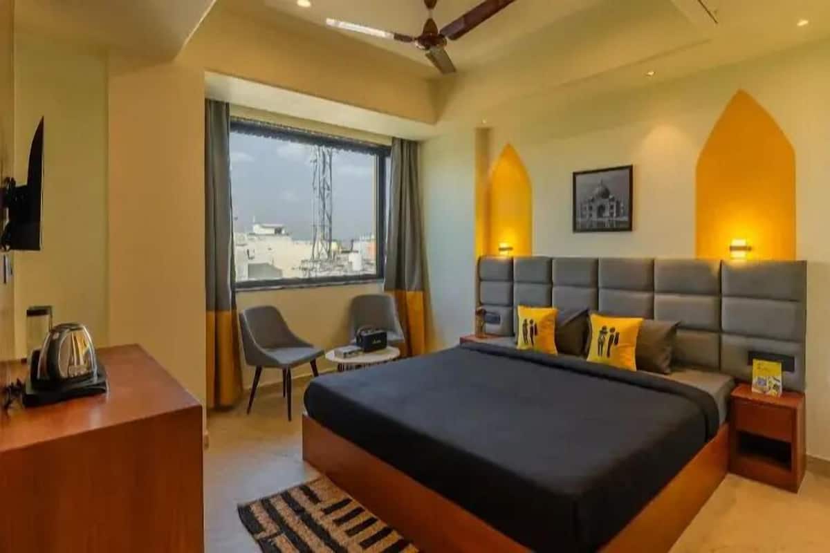 Habitación de hotel moderna con una cama grande, un escritorio, una silla y vistas de la ciudad a través del ventanal.