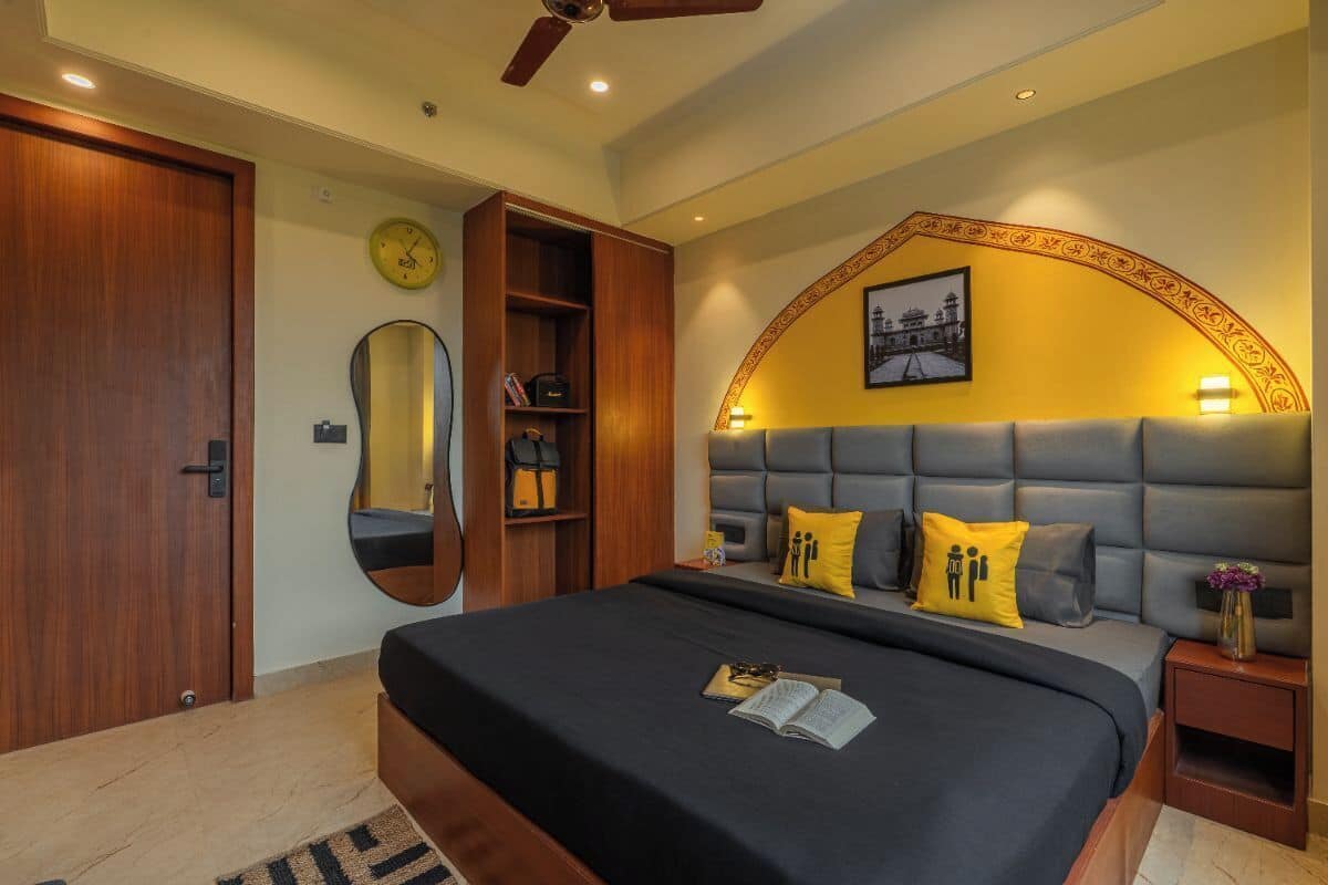 Un dormitorio con una cama grande, un armario de madera, un espejo, una estantería y un arco decorativo en la pared.