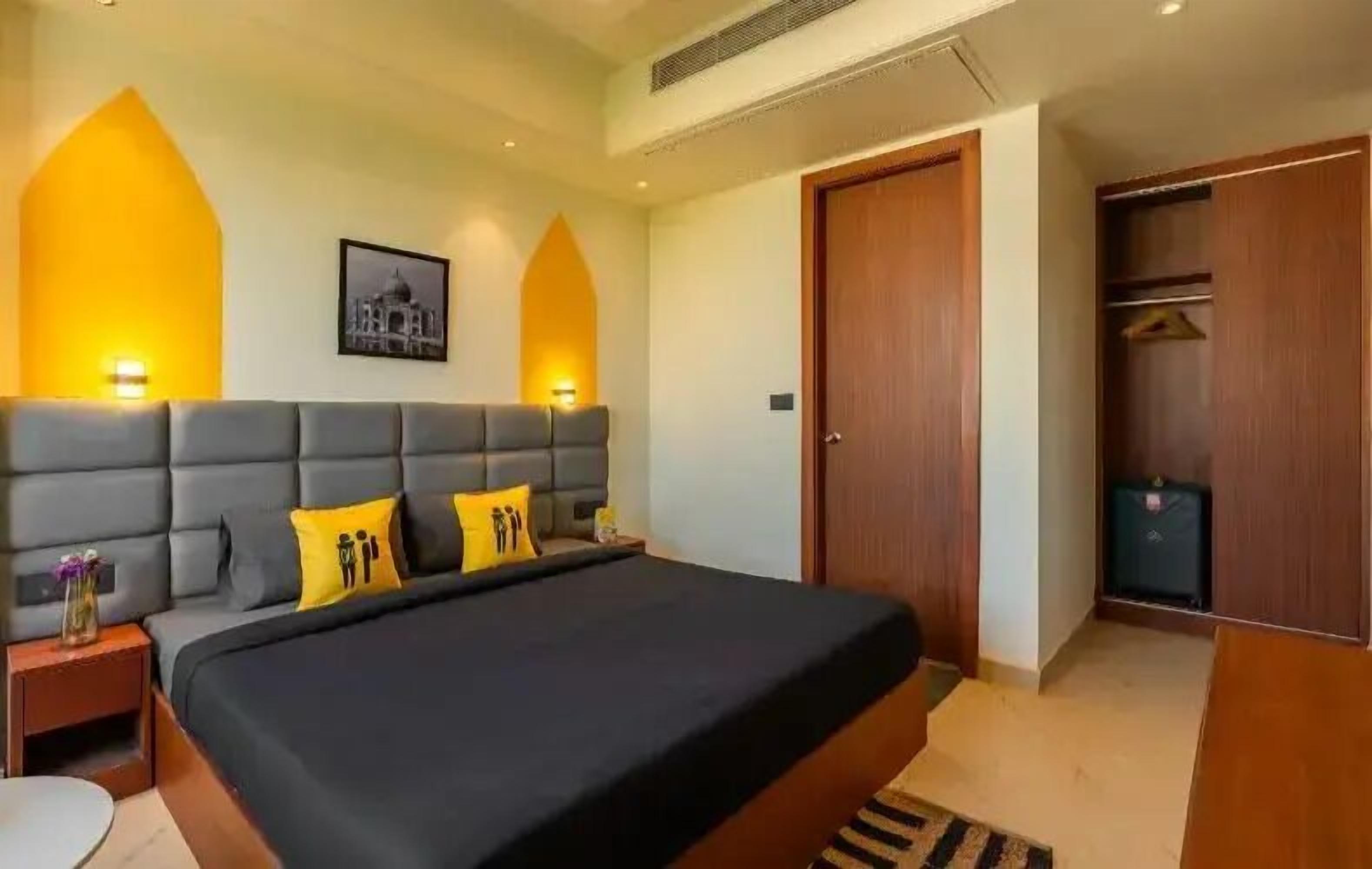 Une chambre à coucher avec un grand lit, deux tables de chevet, une armoire et un tableau encadré au mur.
