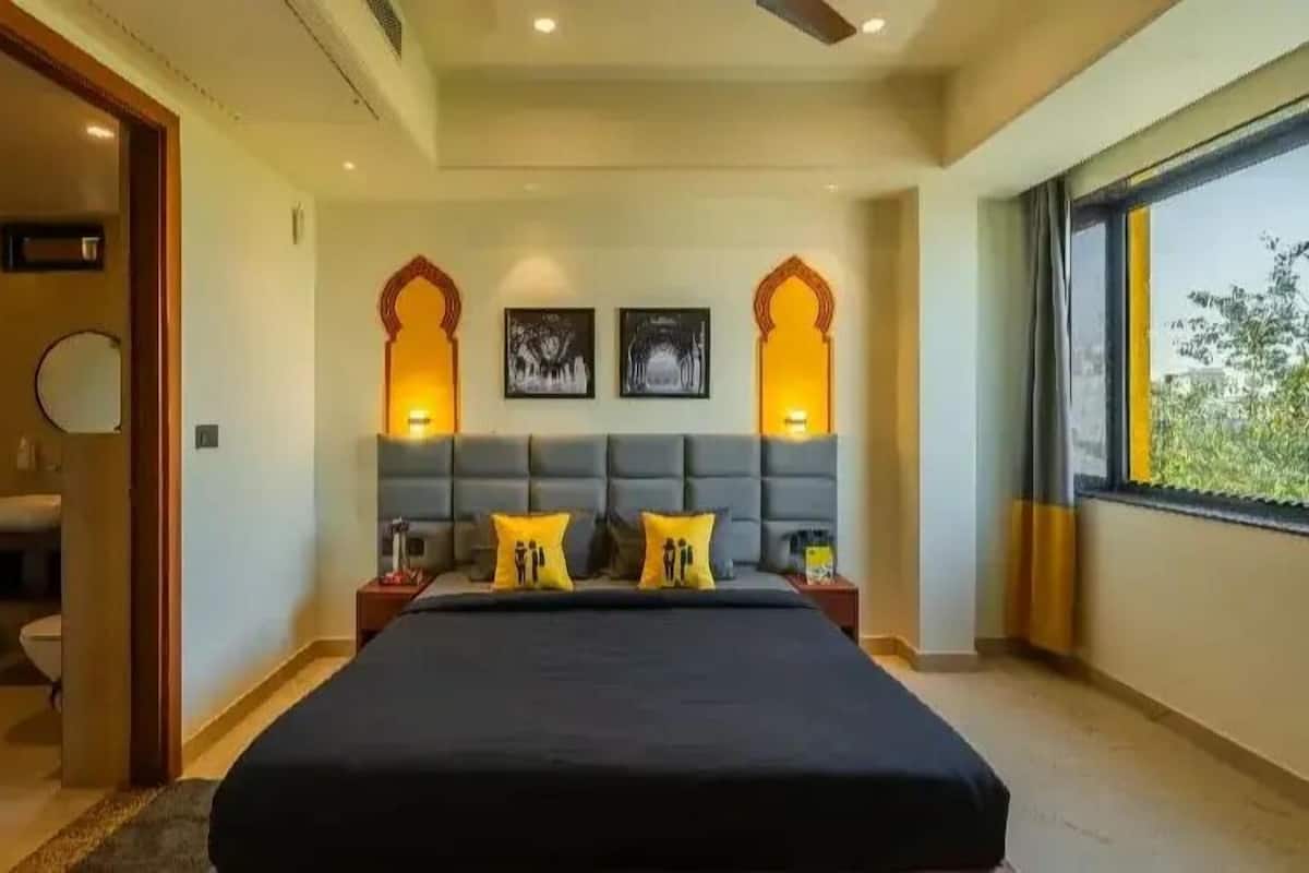 Un dormitorio con una cama grande, dos lámparas de pared y un ventanal con vistas.