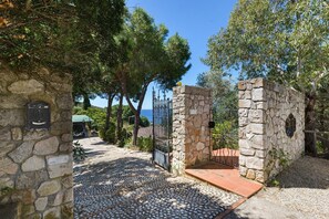 A stone pathway leading to a gated entrance with a stone wall and a sign indicating a 'CAME' area. - Villa Fiorita - Bouganville Apartment: Sea View, Private Pergola, Near Morcone Beach (Capoliveri)