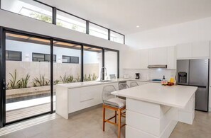 A modern kitchen with a large island, white cabinetry, and a stainless steel refrigerator. - Entire home in Tamarindo, Costa Rica - 10 guests4 bedrooms6 beds3.5 baths (Tamarindo)
