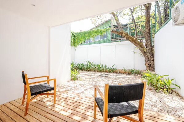 A patio with two wooden chairs and a white wall.