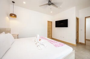 A hotel room with a bed, a television mounted on the wall, and a ceiling fan. - Entire home in Tamarindo, Costa Rica - 10 guests4 bedrooms6 beds3.5 baths (Tamarindo)