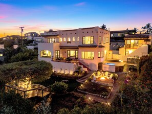 A modern two-story house with a patio, outdoor seating, and a well-lit garden. - Spanish Manor by Coastline Vacation Rentals (San Diego)