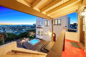 A balcony with a view of a cityscape at dusk, a hot tub, and a red carpeted area. - Spanish Manor by Coastline Vacation Rentals (San Diego)