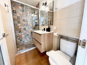 Ein Badezimmer mit Dusche, Toilette, Waschbecken und Spiegel.