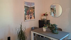 Ein modernes Esszimmer mit Tisch, Stühlen, einer Zimmerpflanze, einem Poster und einem Spiegel an der Wand.