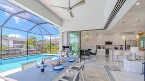 A spacious indoor area with a pool, dining table, and modern kitchen. - Villa Sunshine (Cape Coral)