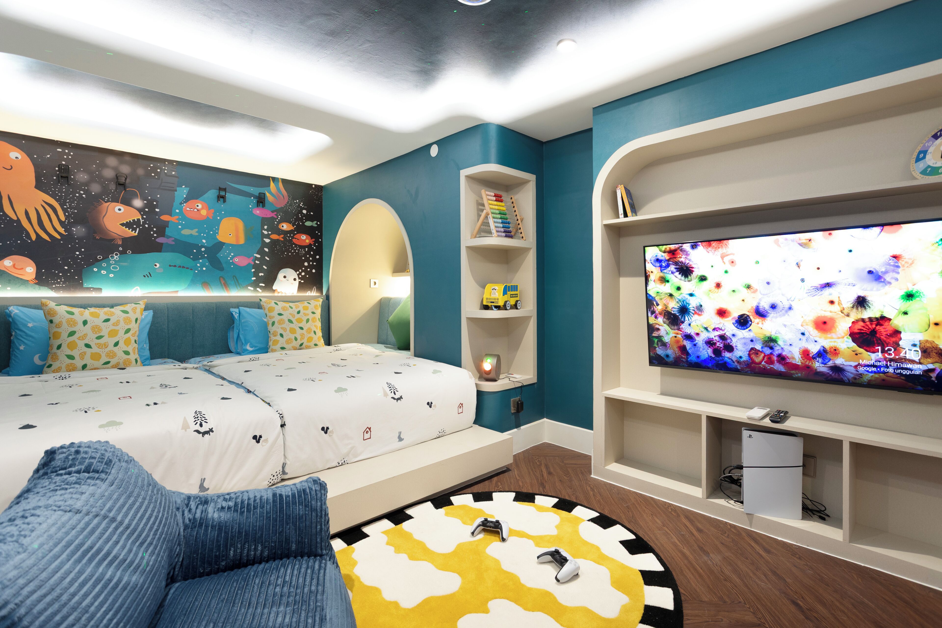 Une chambre à coucher avec un lit, une télévision, une étagère remplie de livres et une fresque murale.