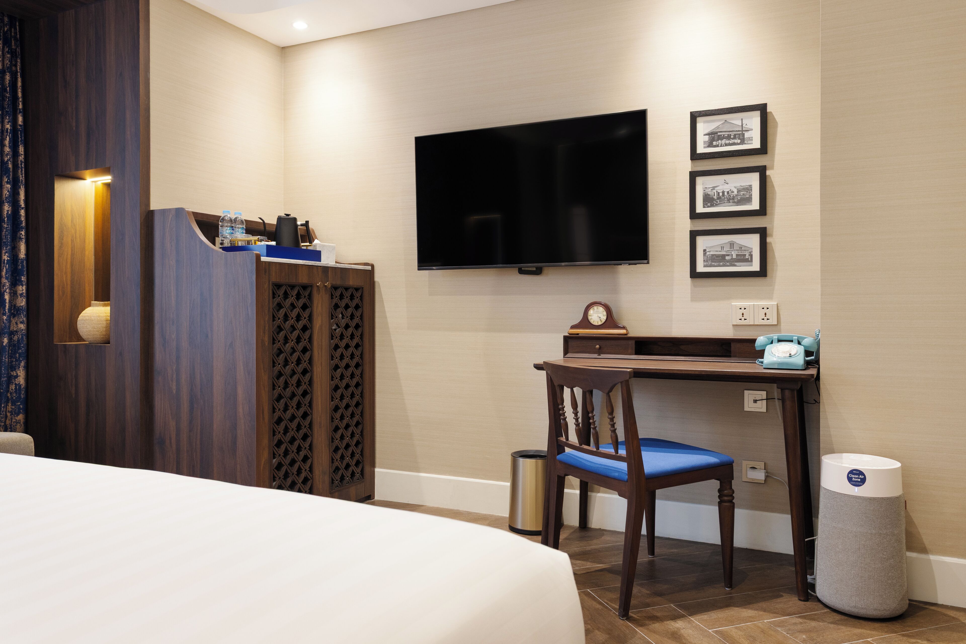 A hotel room with a bed, a desk with a chair, a television, and a trash can.