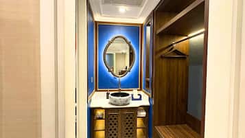 Un bany amb una paret d'accent blau, un mirall rodó, un lavabo amb una bassa decorativa i un armari de fusta.