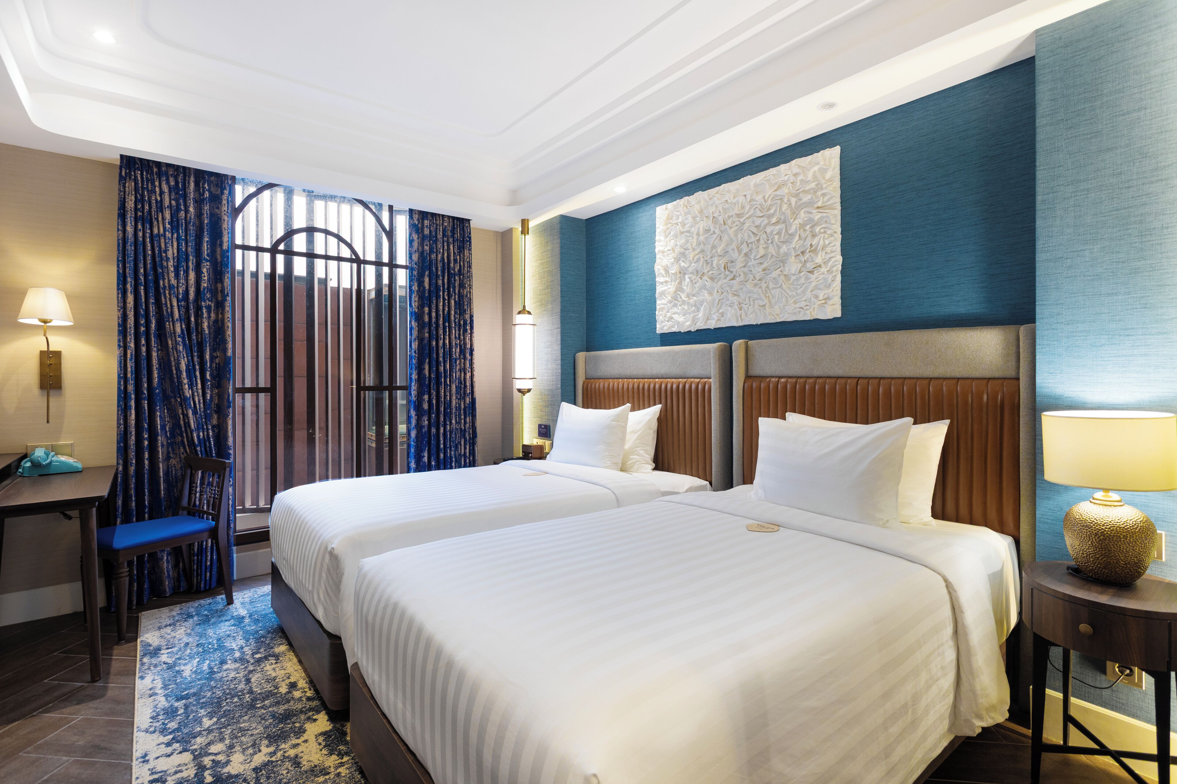 A hotel room with two beds, a desk, and a chair.