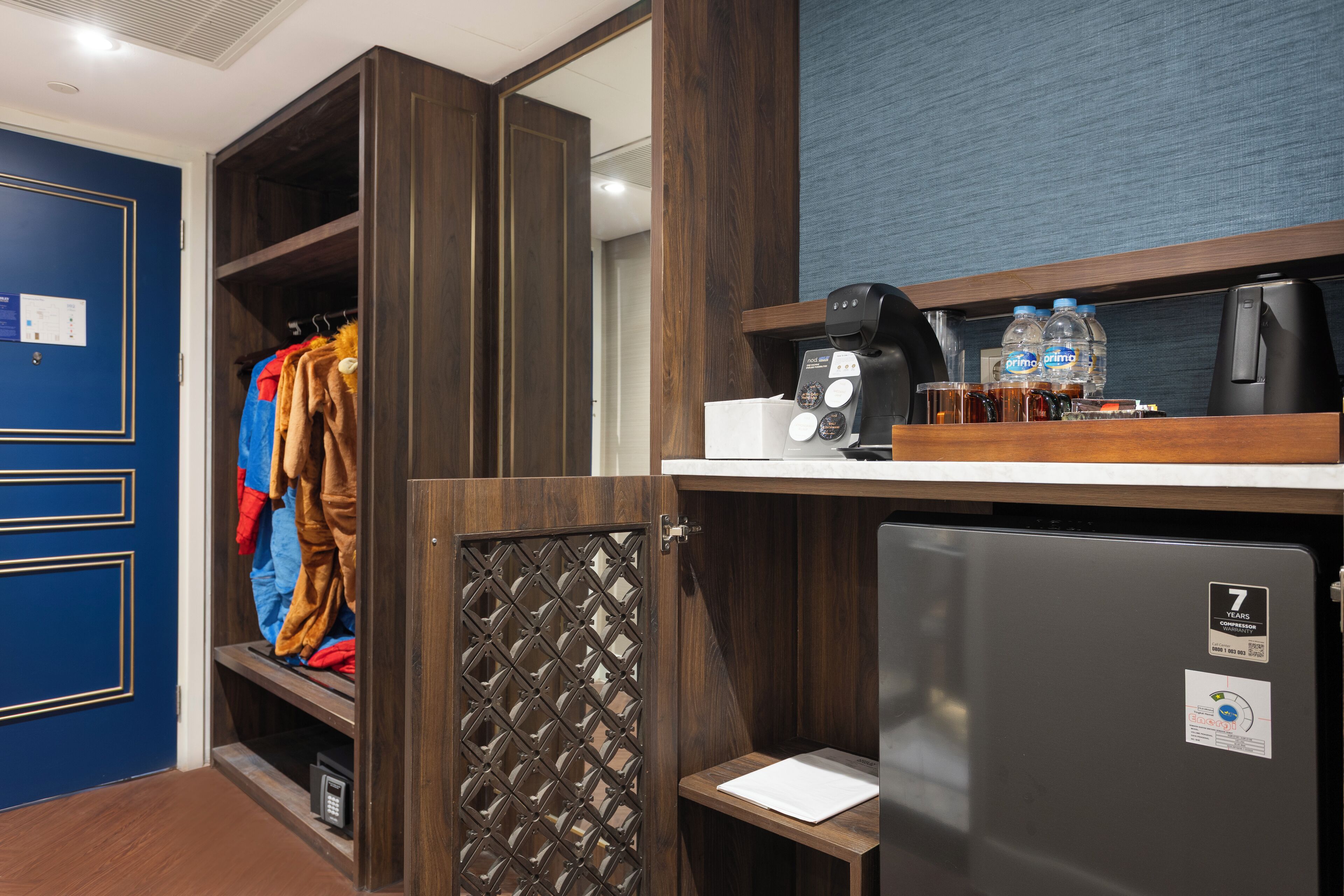 Quarto de hotel com guarda-roupa, minibar e máquina de café.