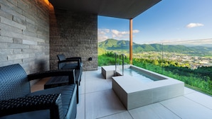 A modern outdoor seating area with a stone wall and a view of a city and mountains. - ENOWA YUFUIN (Yufu)