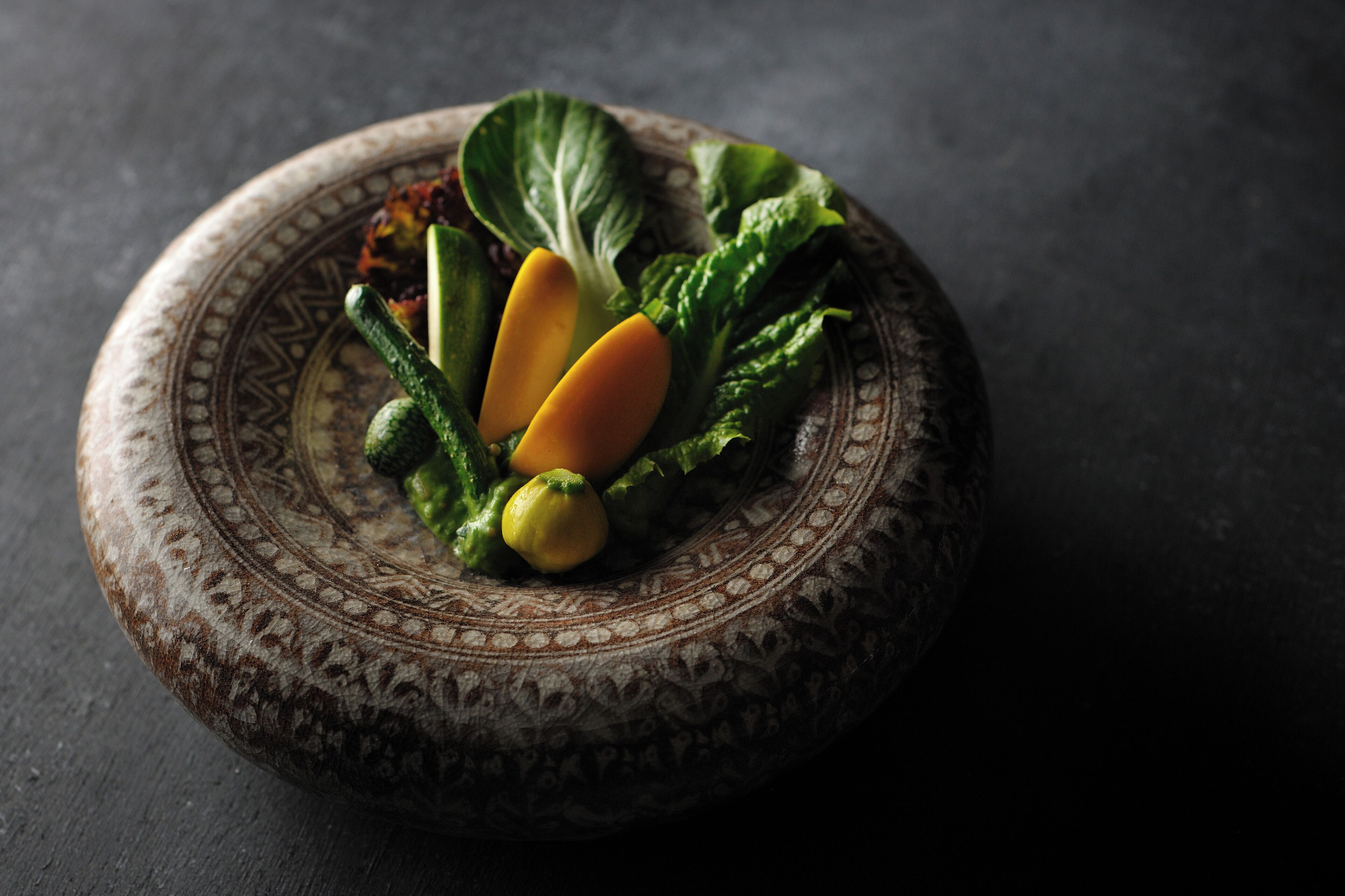 A decorative plate with a patterned design, containing various vegetables.