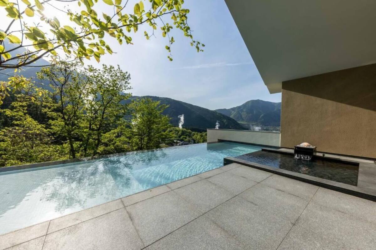 Una piscina infinita moderna con vistas a montañas y vegetación.