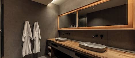 A modern bathroom with two sinks, a large mirror, and towels hanging on the wall.