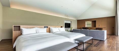 Una habitación de hotel moderna con dos camas grandes, un banco, un escritorio y un espejo.