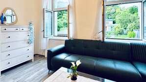 Un salon moderne avec un canapé en cuir noir, une commode blanche et une table basse décorée de bougies.