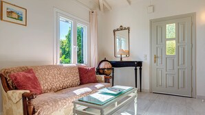 Une pièce comprenant un canapé, une table basse avec un plateau en verre, un globe terrestre, un miroir et une porte avec une fenêtre.