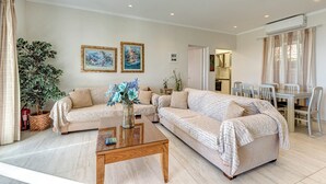 Un salon spacieux comprenant deux canapés, une table basse et un coin repas avec des chaises et une table.