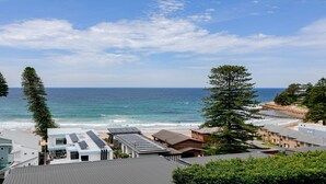 Eine Küstenansicht mit Strand, Meer und Wohnhäusern mit Solaranlagen.