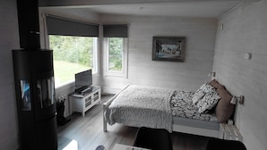A bedroom with a bed, a fireplace, a TV, and a window. - In the land of the Lapps Villa Pakatti (Kittilä)