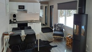 A modern kitchen with white cabinets, a coffee maker, and a dining area with a black leather chair. - In the land of the Lapps Villa Pakatti (Kittilä)