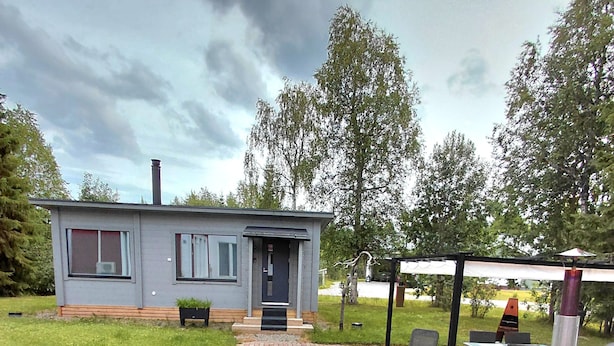 A modern house with a brick pathway leading to a patio area with outdoor furniture and a barbecue grill. - In the land of the Lapps Villa Pakatti (Kittilä)