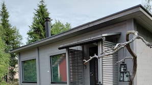 A modern single-story house with a grey exterior, a black door, and a small porch with steps leading to the entrance. - In the land of the Lapps Villa Pakatti (Kittilä)