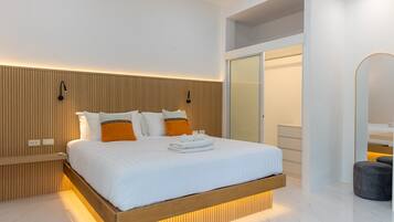 Ein modernes Hotelzimmer mit einem Holzkopfende, einem großen Bett mit weißer und orangefarbener Bettwäsche, einem Nachttisch mit Lampe und einem Kleiderschrank mit Spiegel.