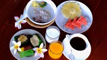 A table with a bowl of soup, a plate of fruit, a plate with a dessert, a glass of juice, and a cup of coffee.