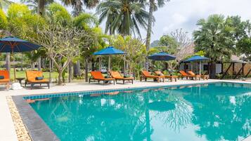 Alberca al aire libre, sombrillas en la alberca y camastros