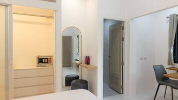 Una habitación de hotel moderna con cama, escritorio, silla, espejo y armario.