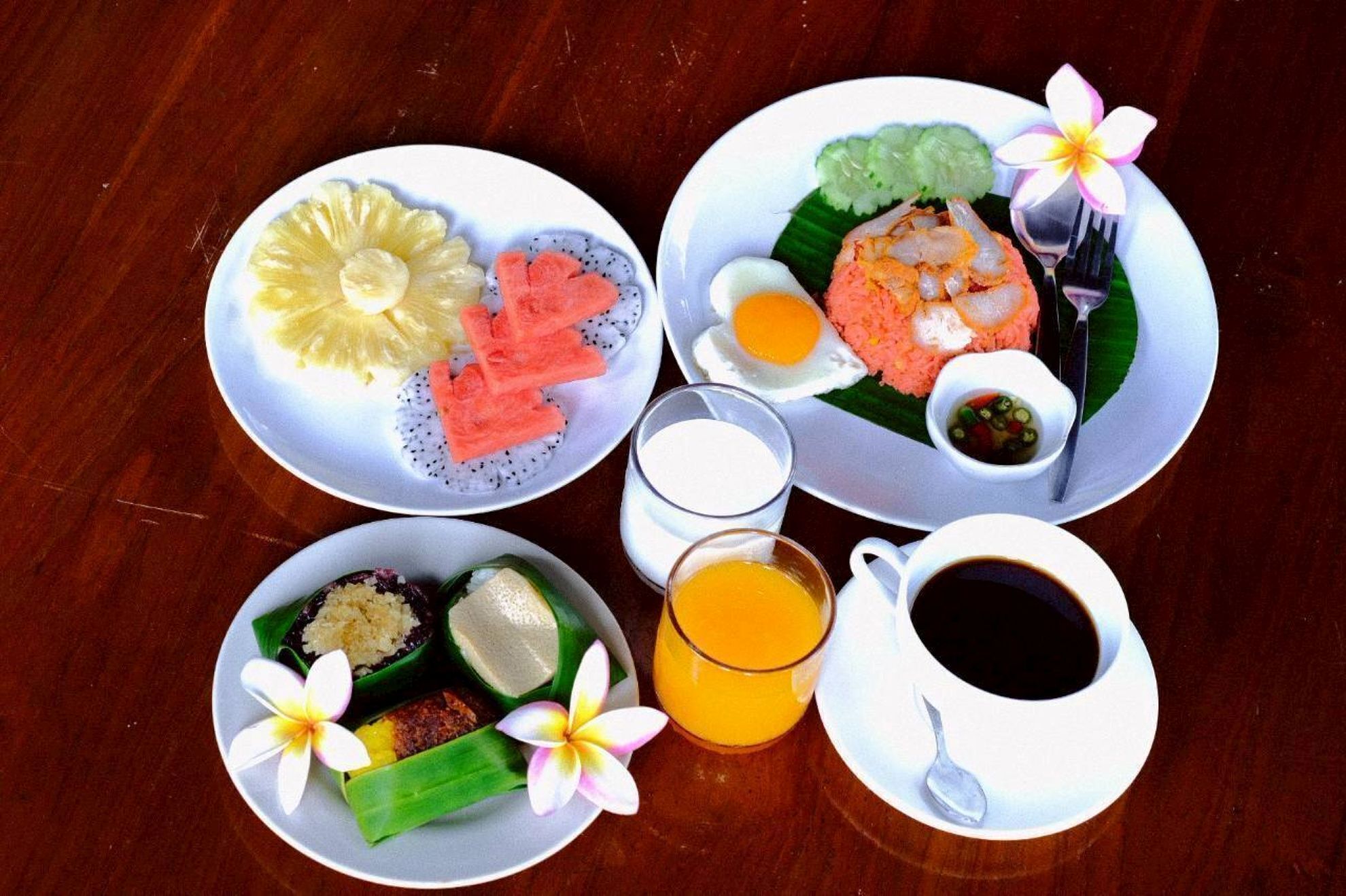 Ein Tisch mit vier Tellern Essen, zwei Gläsern Saft und einer Tasse Kaffee.