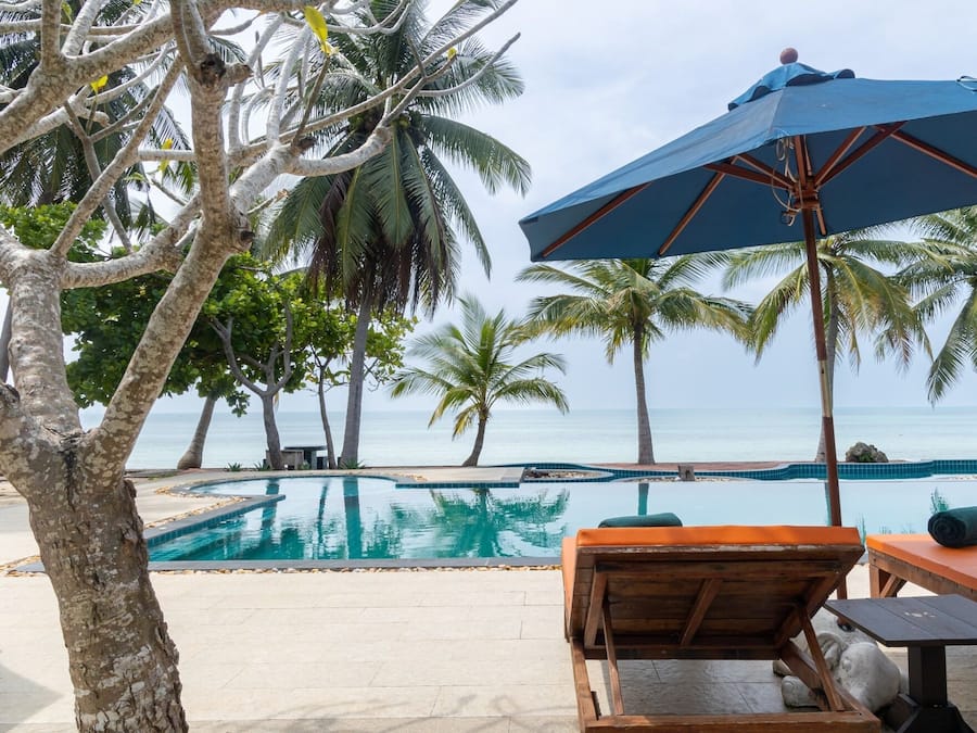 Una piscina al aire libre, sombrillas, sillones reclinables de piscina