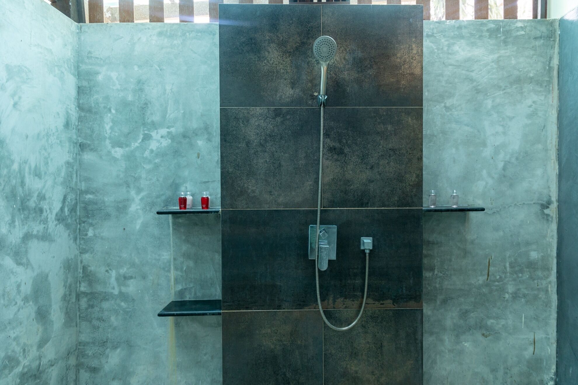 A shower enclosure with a handheld showerhead and a wall-mounted control panel.