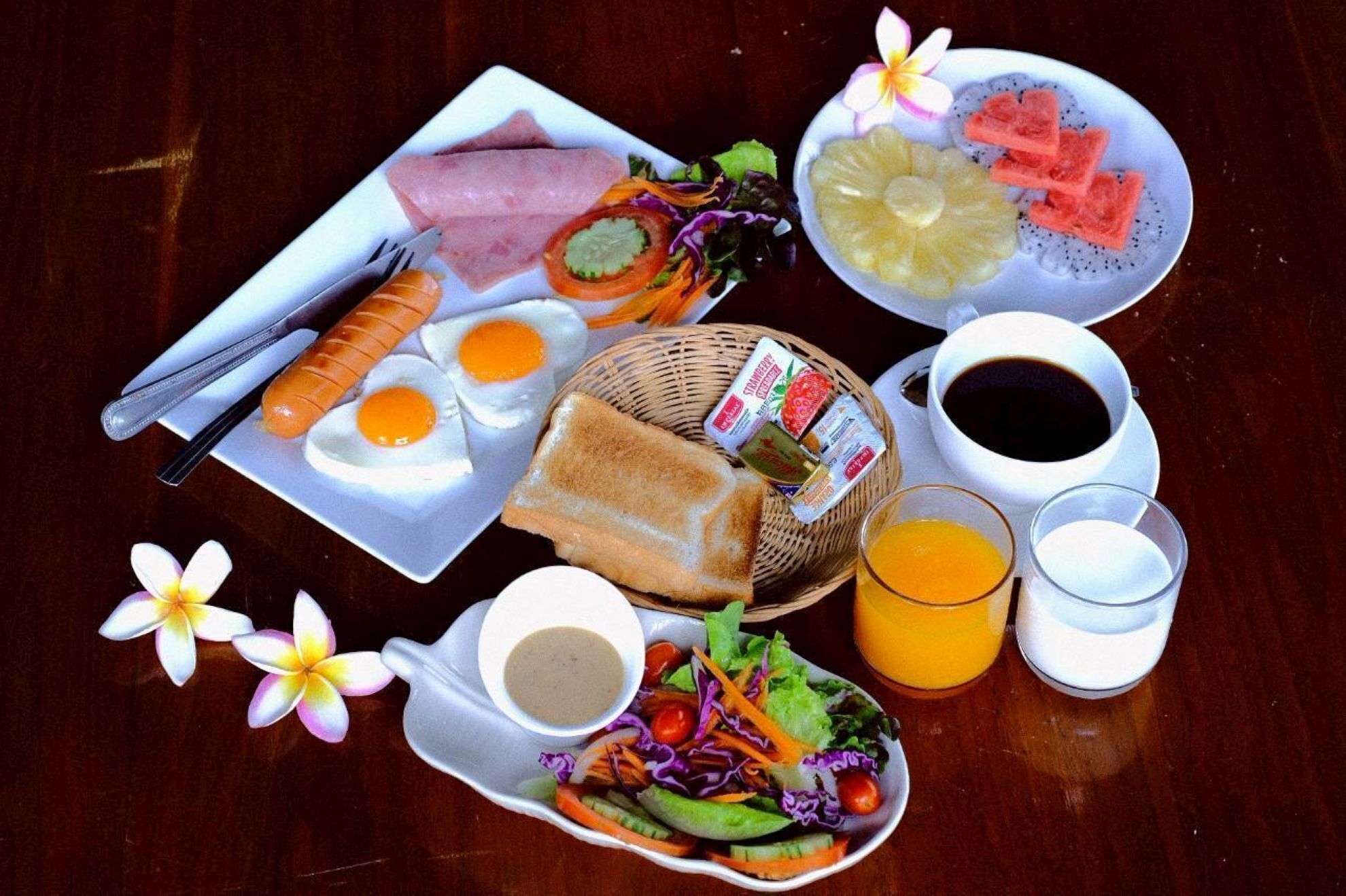 Een ontbijttafel met diverse gerechten, waaronder eieren, toast, een salade en fruit.