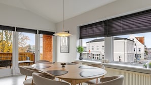 Een moderne eethoek met een grote tafel, zes stoelen en een hanglamp.