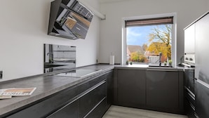 Een moderne keuken met donkere kastjes, een inbouwoven en een raam met uitzicht.