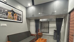 A compact living space with a sofa, wooden table, and cabinets. - KRS Paradise By  K Hotels  (Tiruvannamalai)